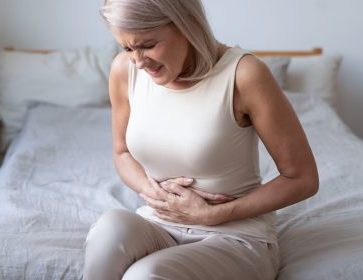 Unhealthy mature woman holding belly, suffering from pain